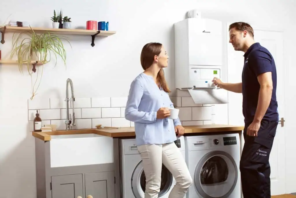 Heating engineer servicing a boiler for a homeowner